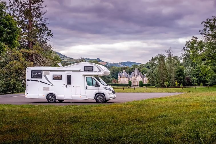 Camping-car stationné sur un parking devant un château