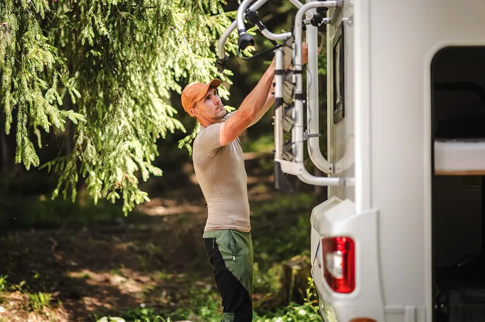 Homme vérifiant son porte-vélà à l'arrière du camping-car